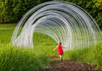 Photo of little girl running through metal arcs of a tree house at the Minnesota Landscape Arboretum's tree houses exhibit.