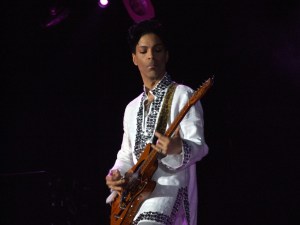 Photo of a man playing guitar in a white suit