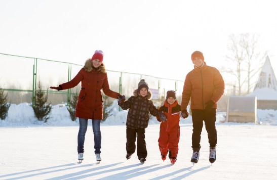 Family Ice Skating on outdoor ice rink. Family friendly holiday events.