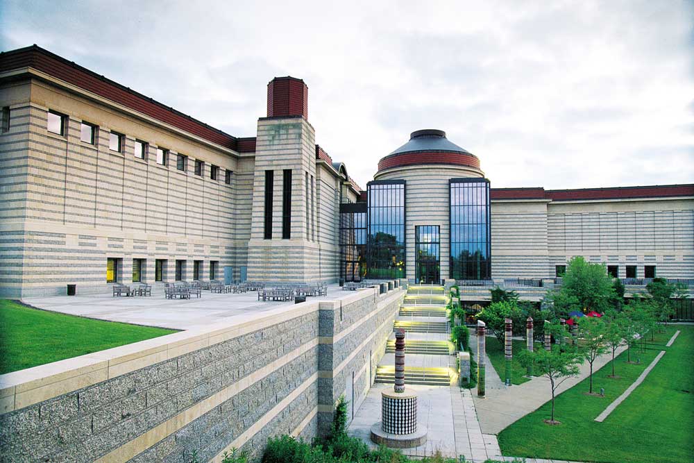 The Minnesota History Center with a finely manicured, green lawn in front on a sunny day.