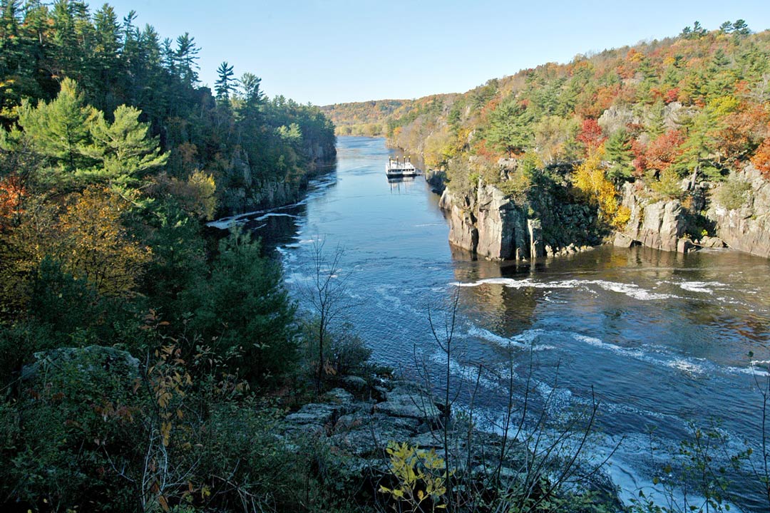 An overlook of the St. Croix River during the fall with a cruise boat on its waters.