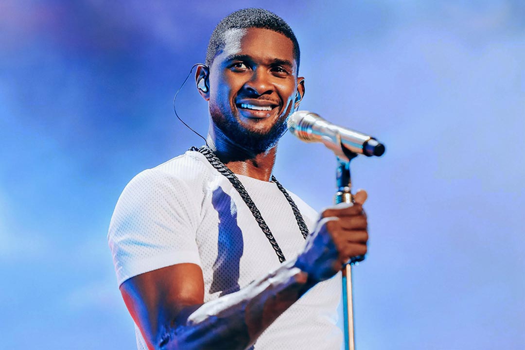 A picture of Usher performing and holding a microphone stand.